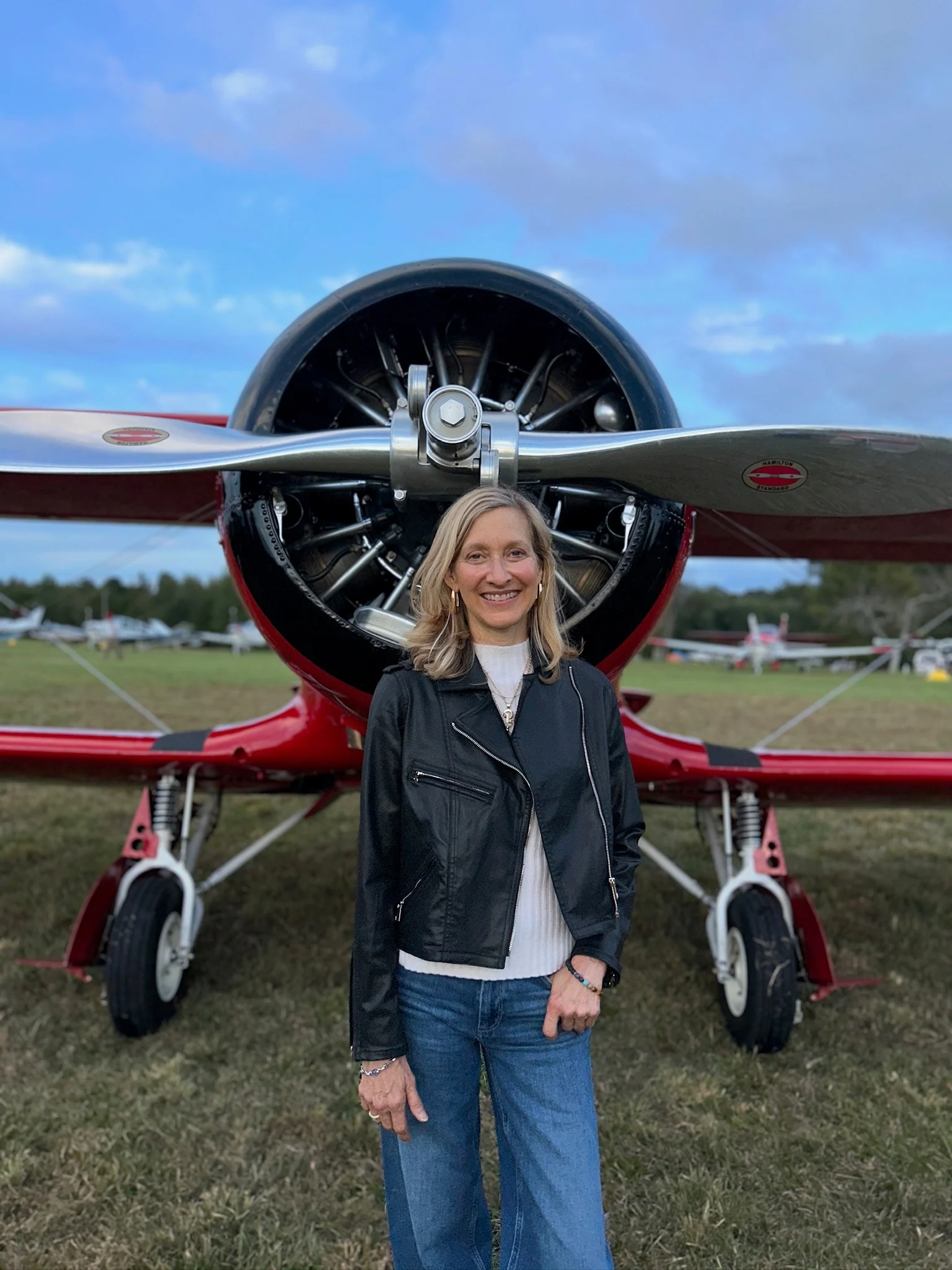 Jennifer Pitt standing in front of a red Staggerwing, under its propeller