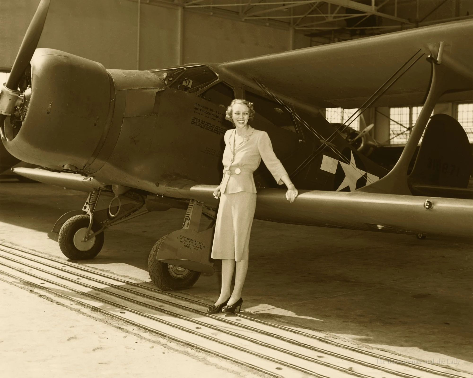 Olive Ann Beech standing beside the wing of a Staggerwing in a hangar