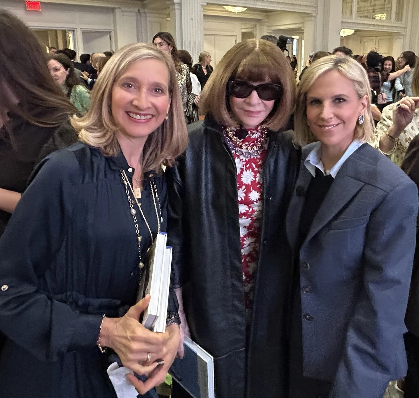 Jennifer Pitt with Tory Burch and Anna Wintour in a crowded event hall