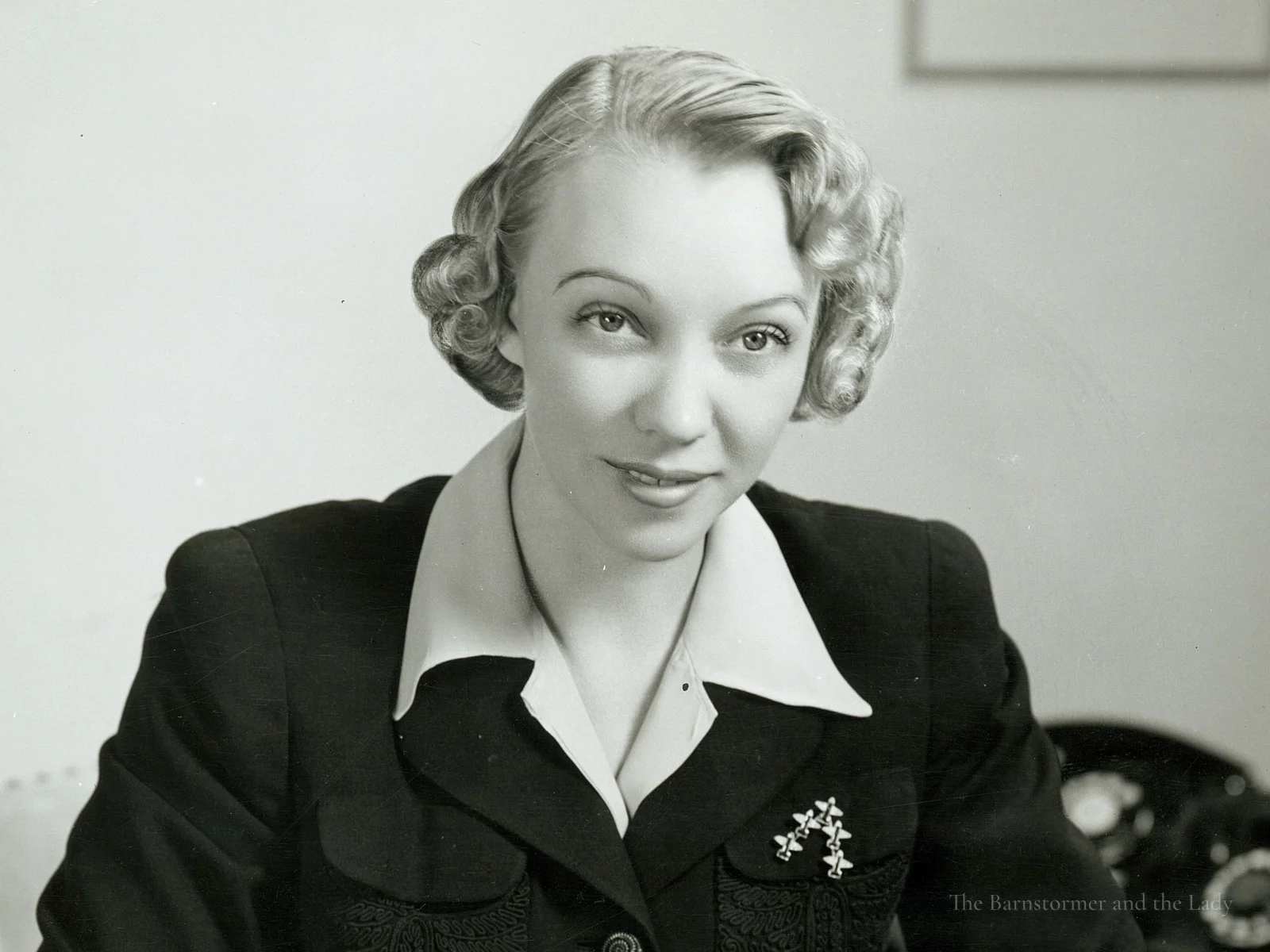 Olive Ann Beech seated at a desk, writing with a pen
