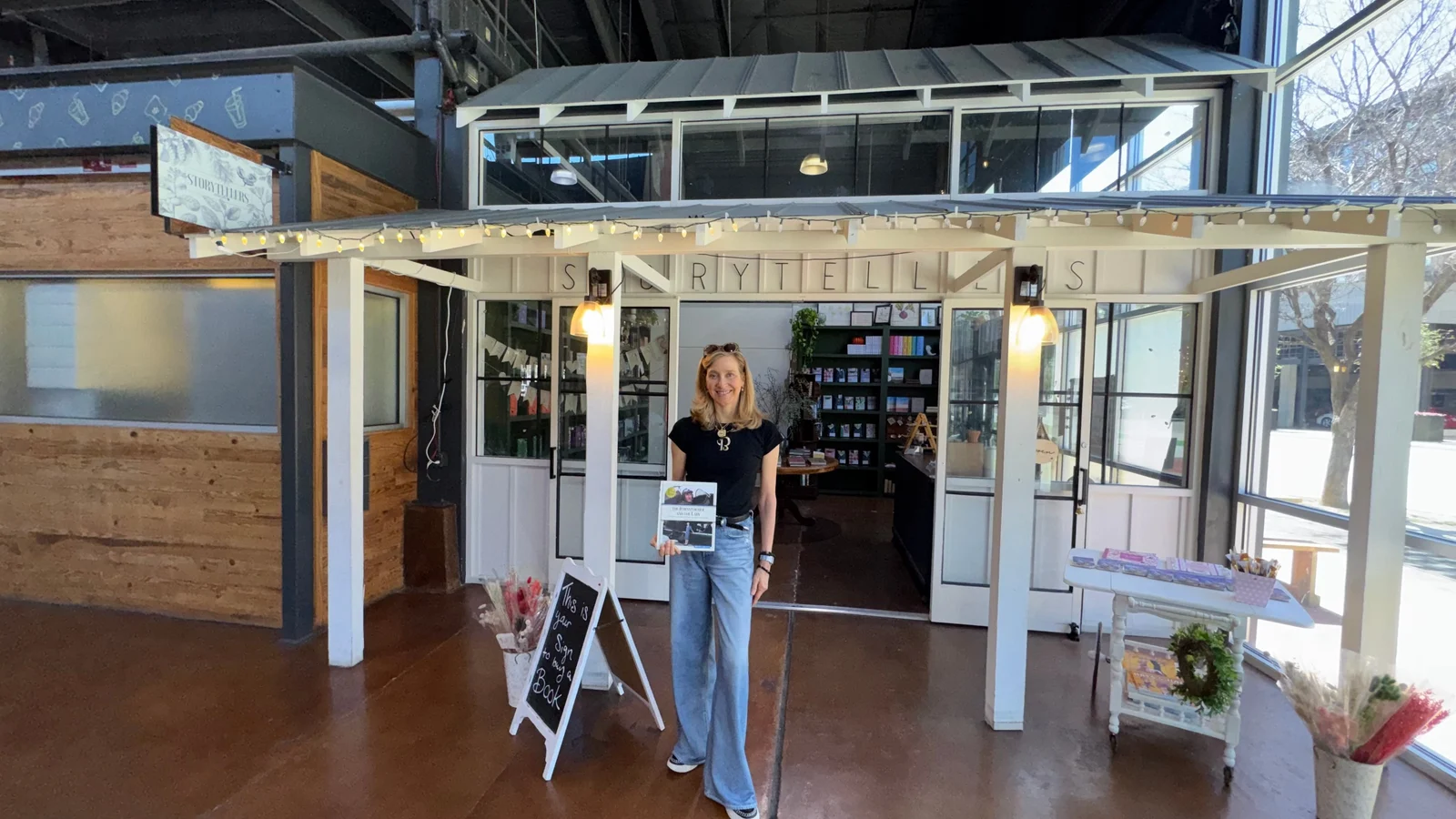Jennifer Pitt holding the book in front of the Storytellers shopfront