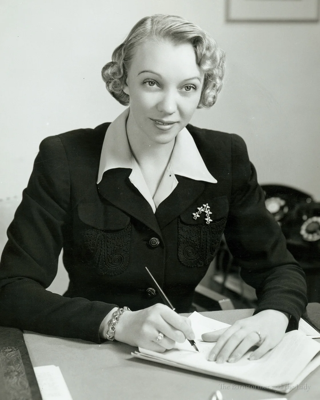Olive Ann Beech seated at a desk, writing with a pen